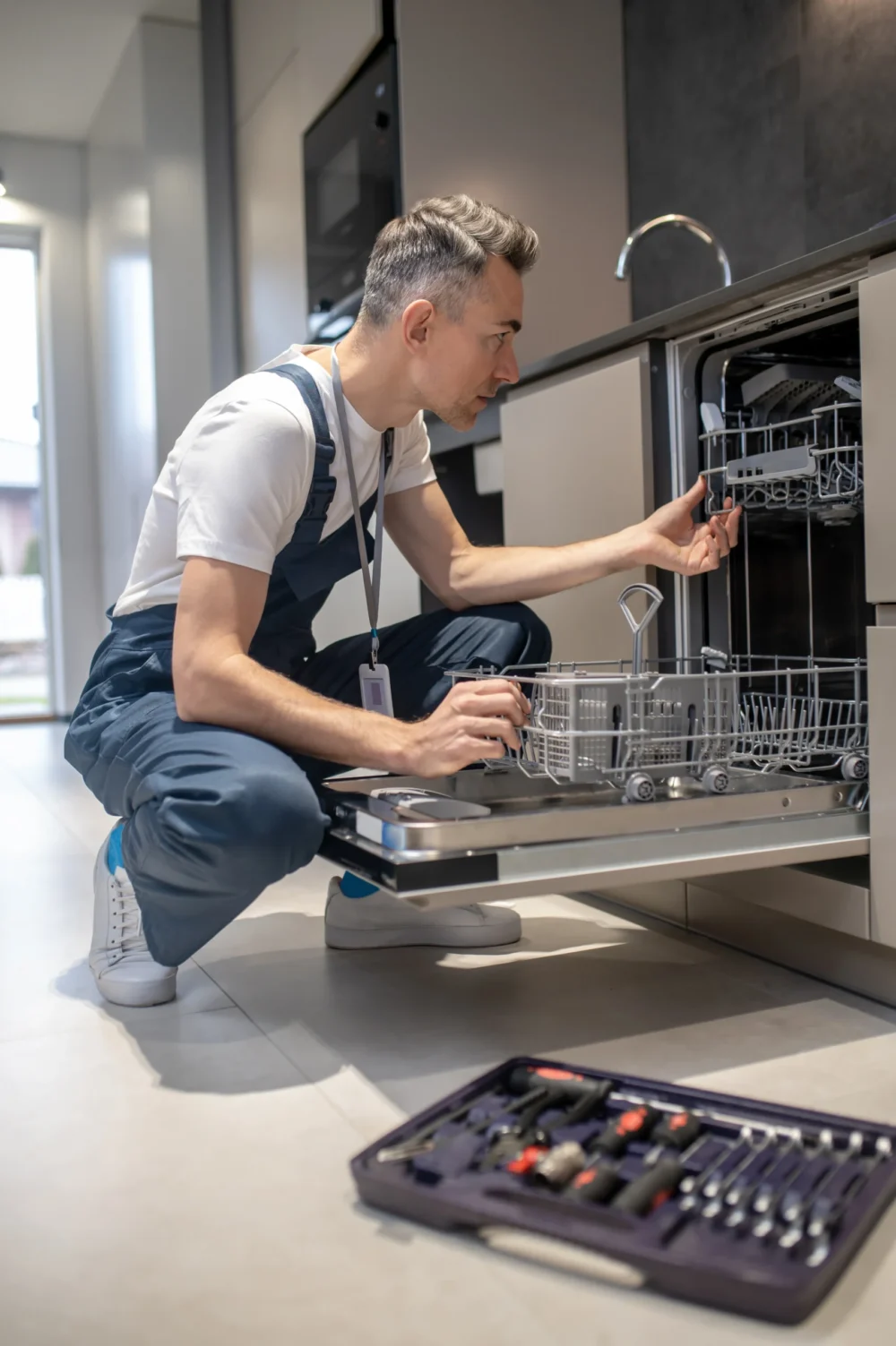 Technician repairing a leaking dishwasher in a kitchen in Albany NY
